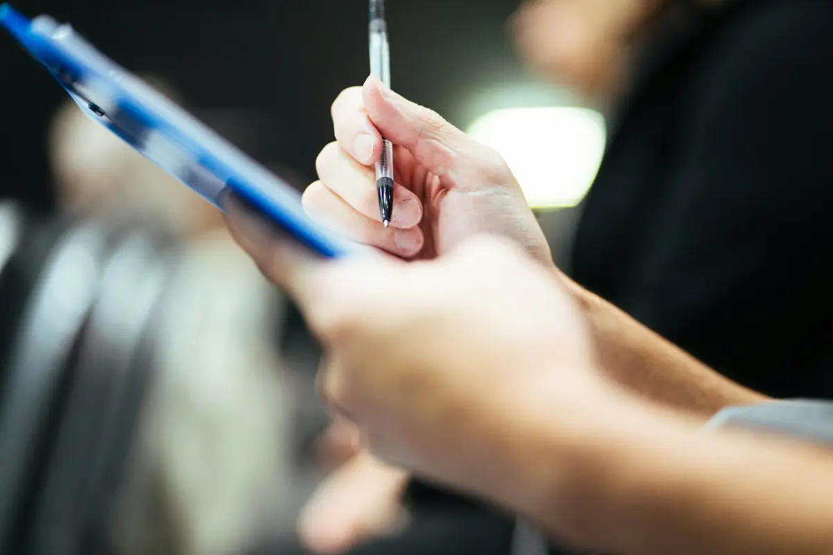 Hand met een telefoon en een pen, klaar om een formulier in te vullen