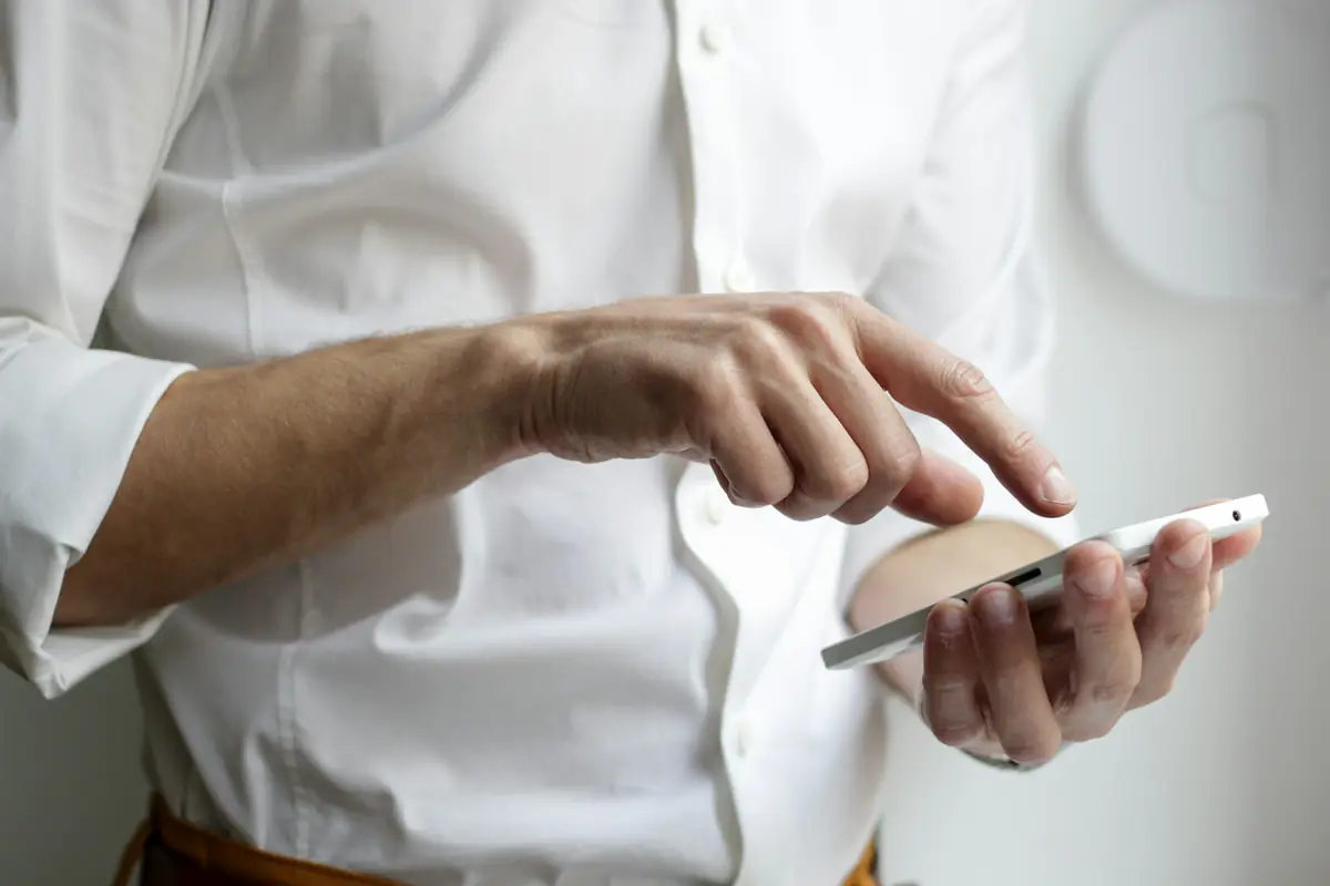 Iemand in een wit overhemd gebruikt zijn telefoon