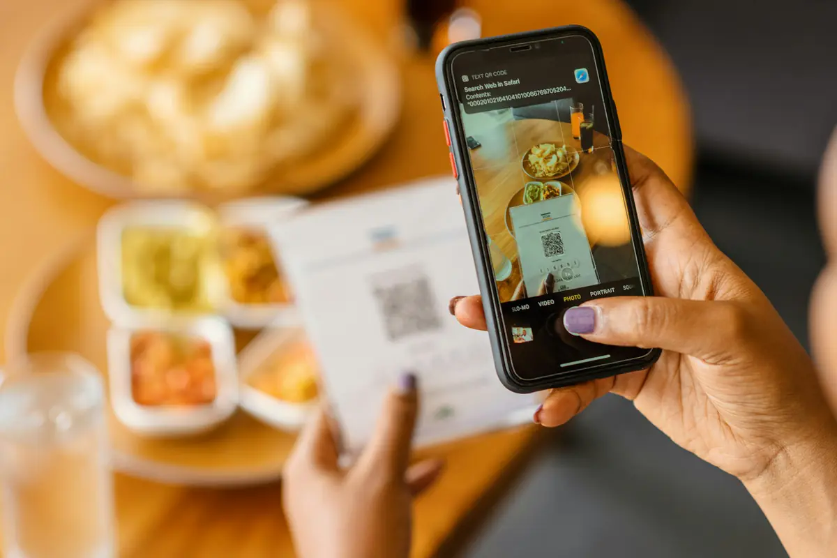 Telefooncamera scant de QR-code van een menukaart aan tafel